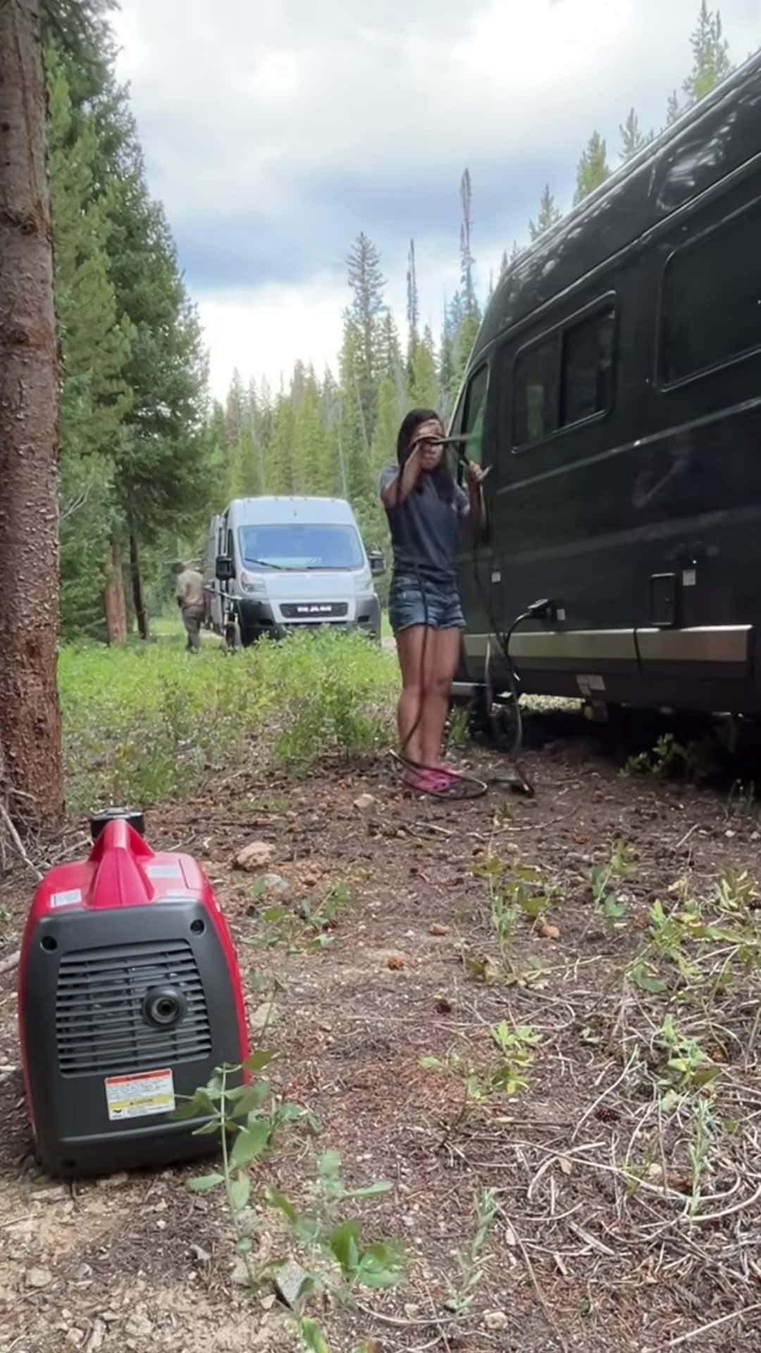 Portable Honda generator running next to a camper van under grey skies