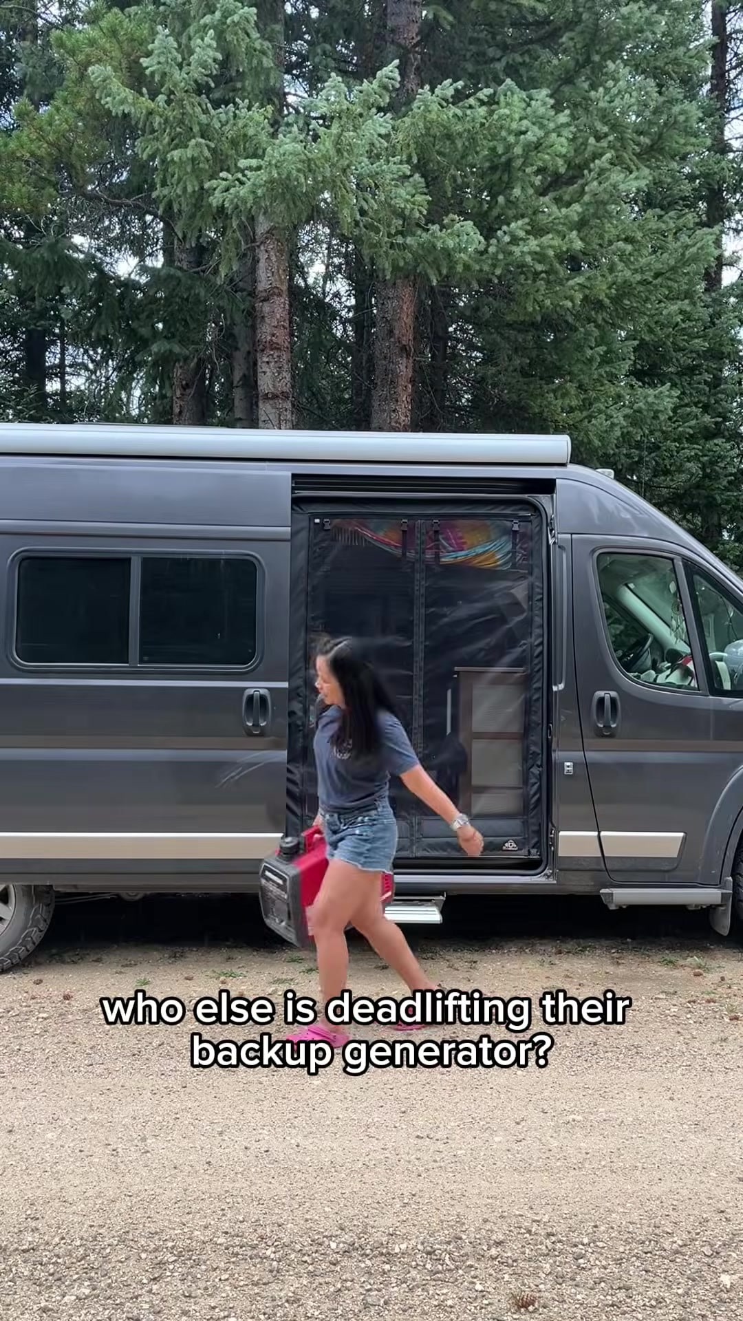 Woman carrying a heavy portable generator beside a camper van