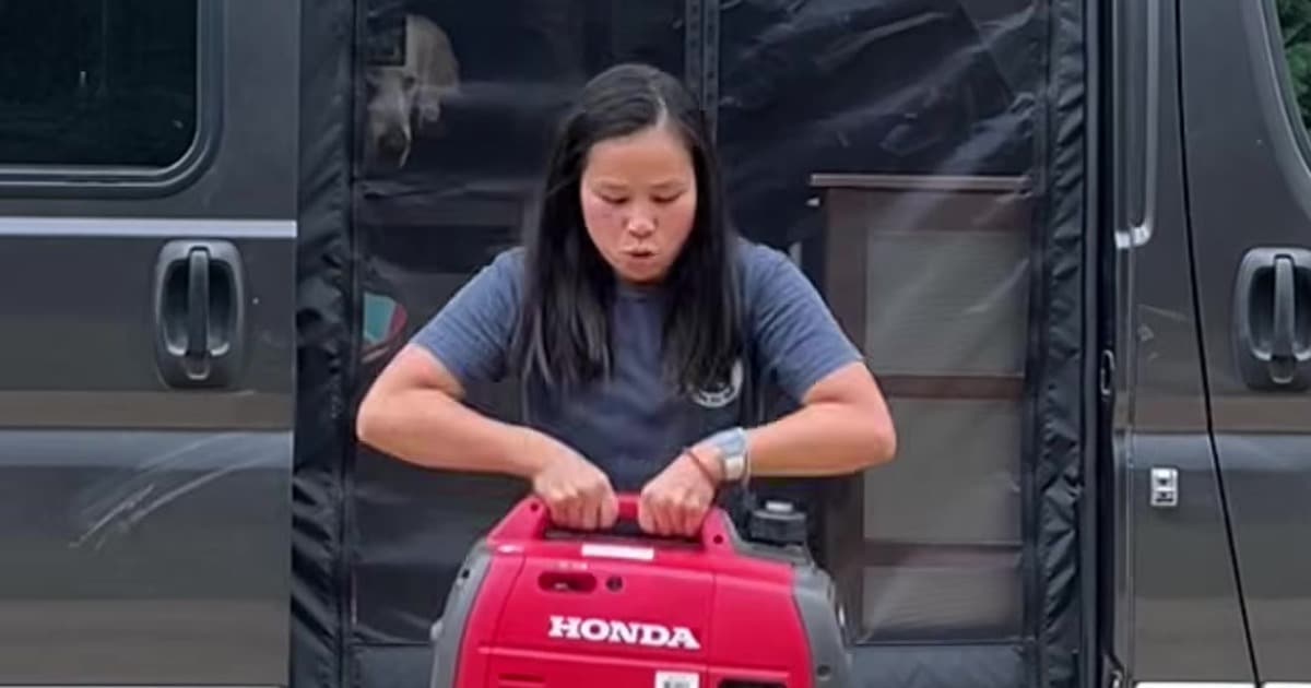 Woman lifting a portable Honda generator out of a camper van on a cloudy day
